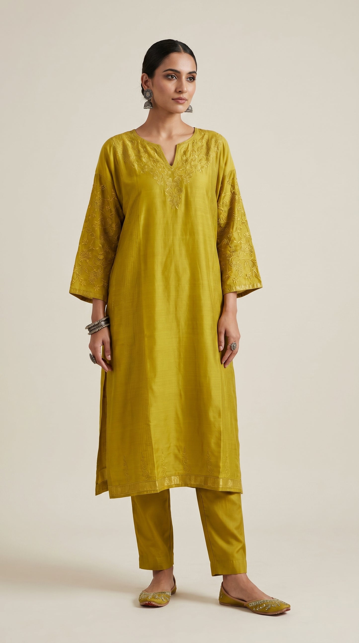 Woman wearing a mustard yellow kurta with pants on a beige background