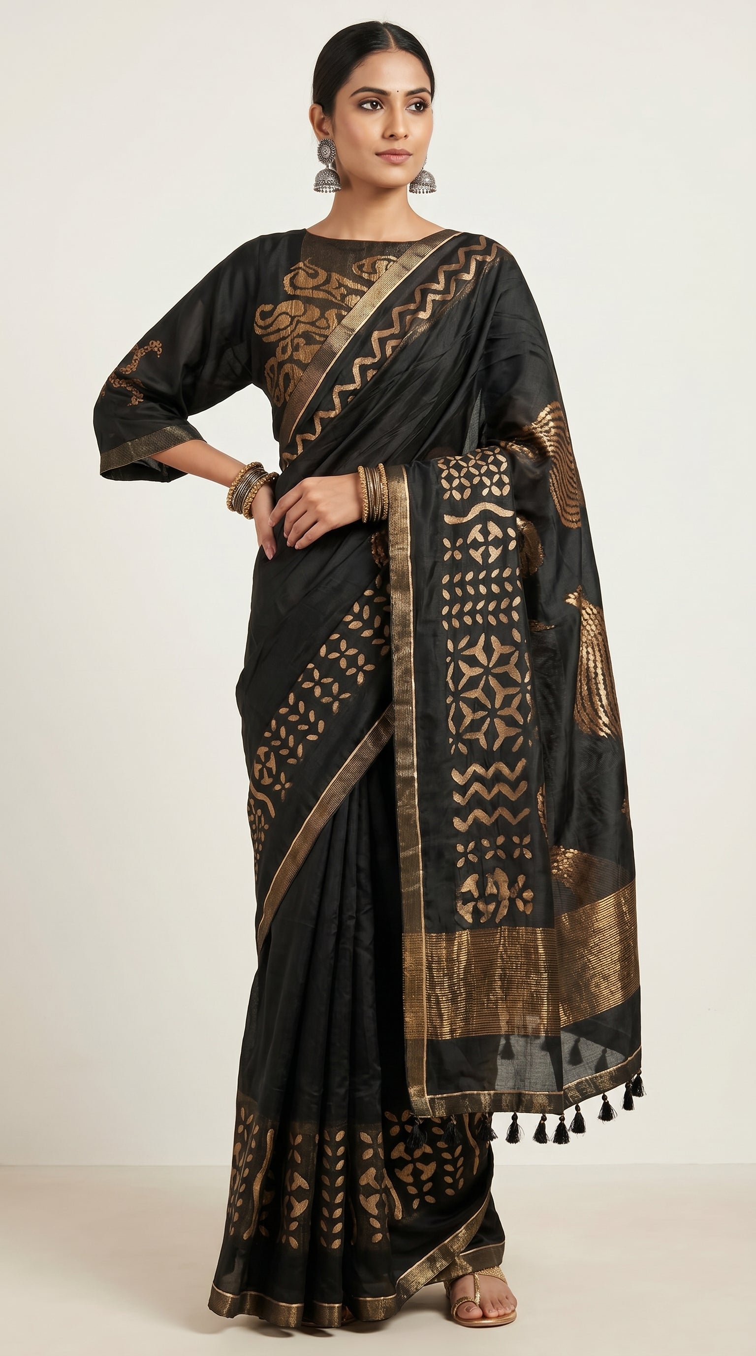 Woman wearing a black saree with gold patterns on a white background