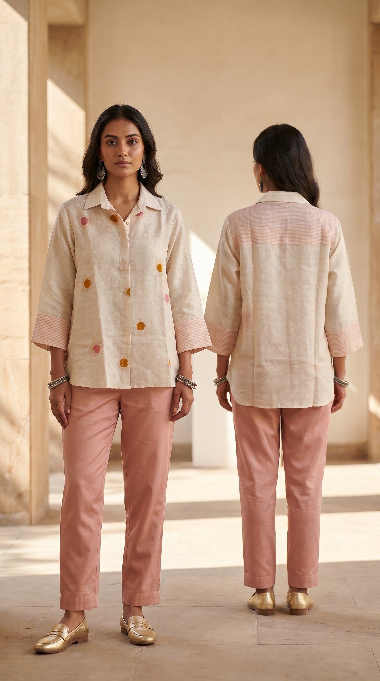 Woman wearing a beige shirt and pink pants standing in a sunlit room.