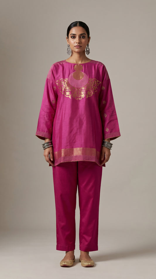 Woman wearing a magenta traditional outfit with gold embroidery on a beige background