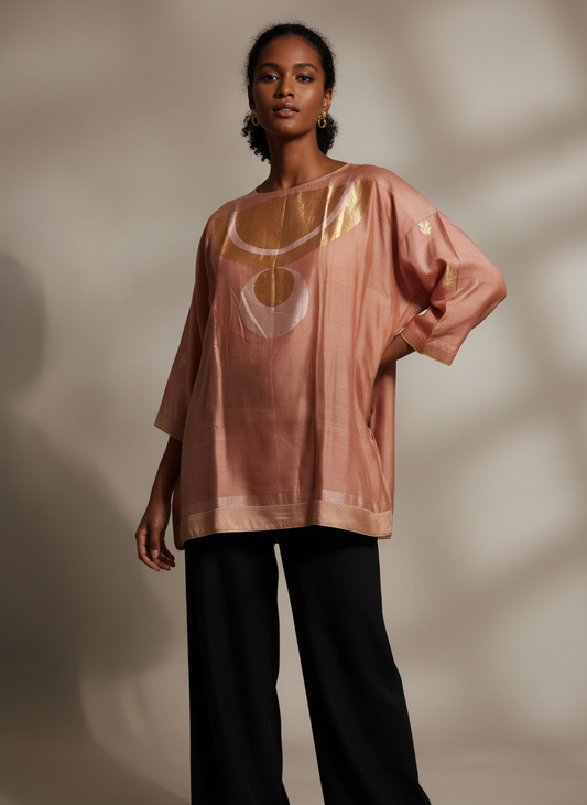 Woman wearing a pink oversized tunic with a graphic design on a neutral background