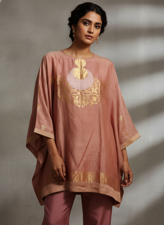 Woman wearing a pink traditional outfit with gold embroidery against a neutral background