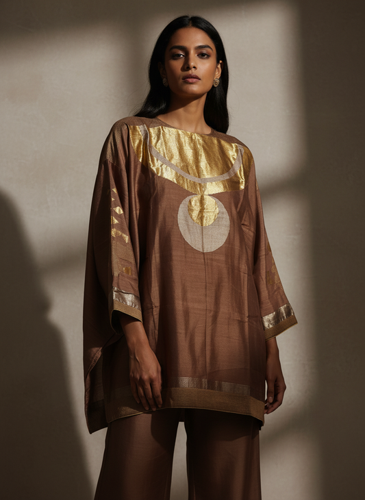 Woman wearing a brown dress with gold weaving against a neutral background