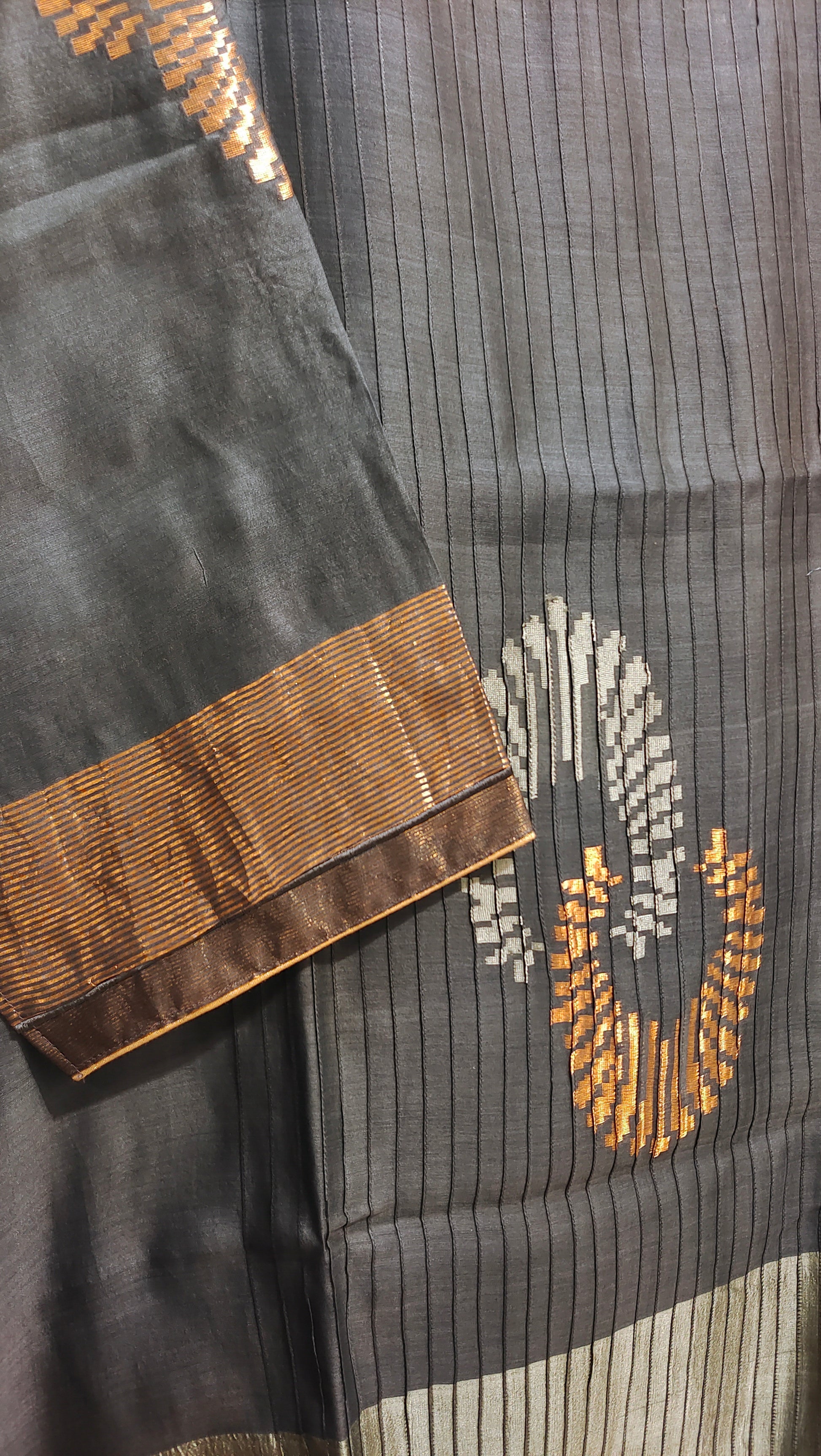 Gray fabric with gold embroidery on a wooden surface