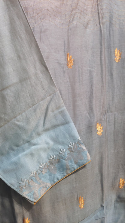 Light blue fabric gold embroidery on a wooden surface