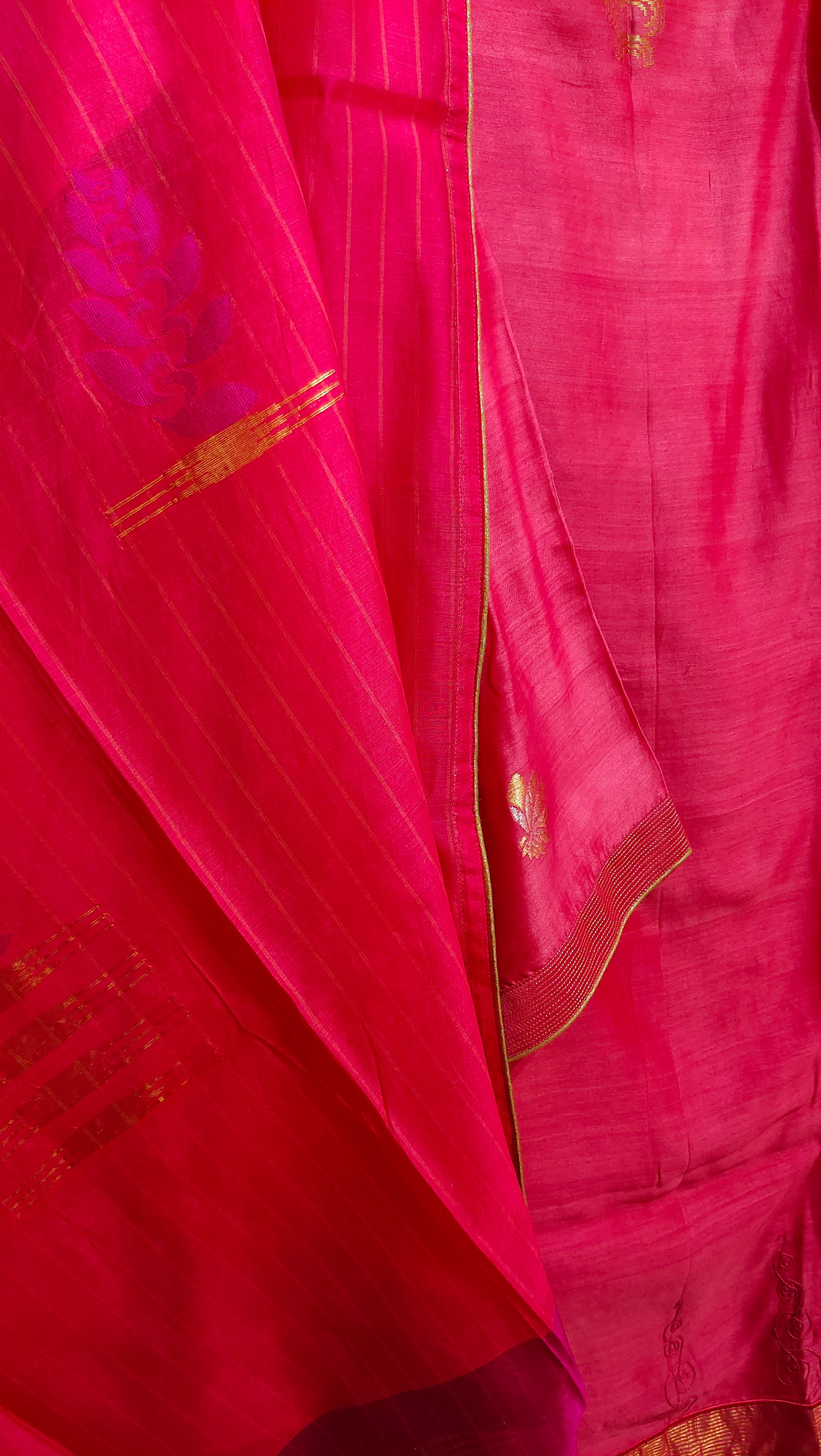 Close-up of a pink suit with gold border and floral design.