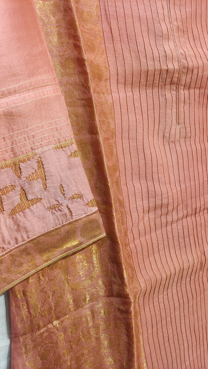 Close-up of a pink tunic with gold border and intricate patterns.
