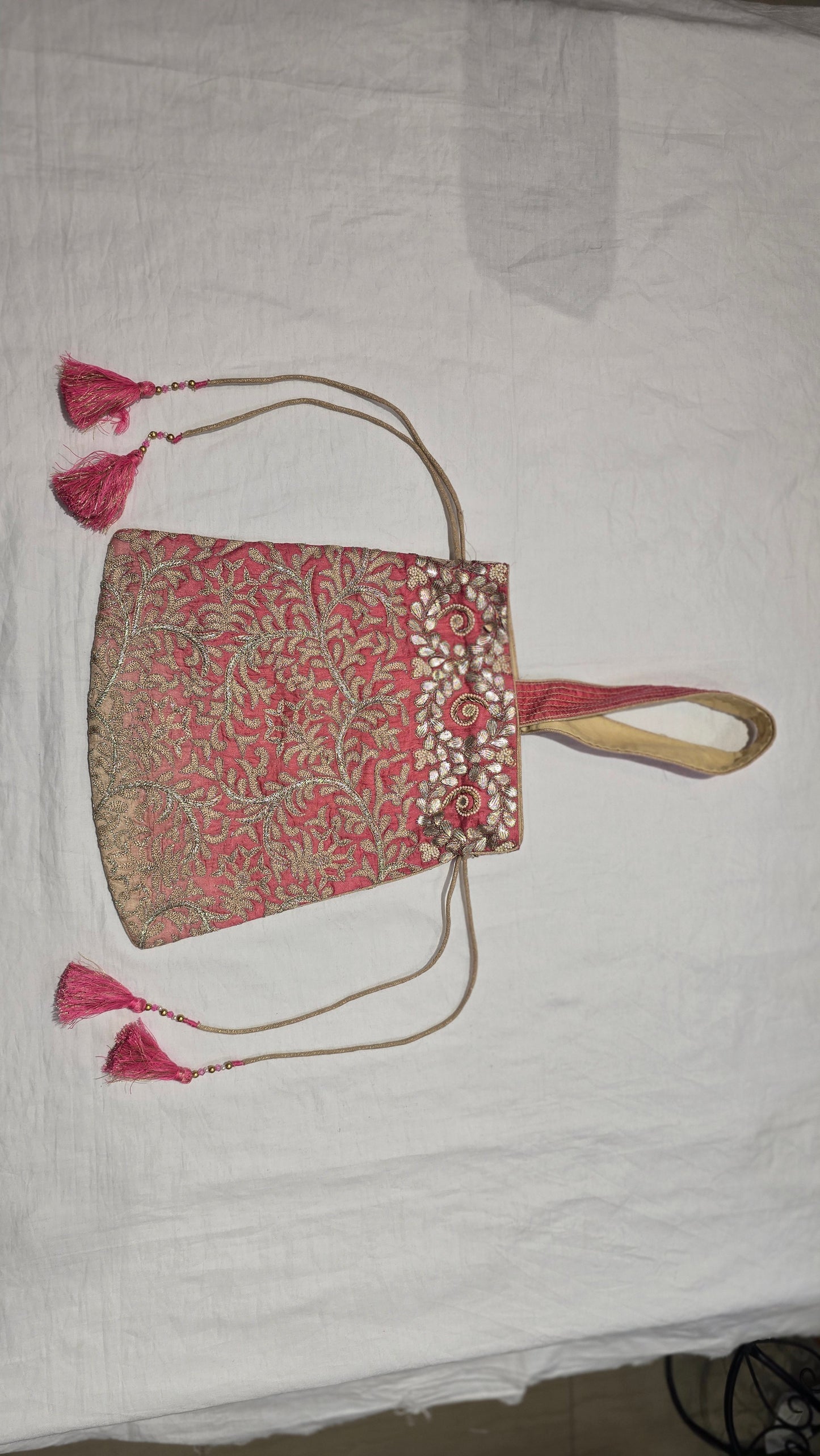 Decorative pink handbag with tassels on a white background