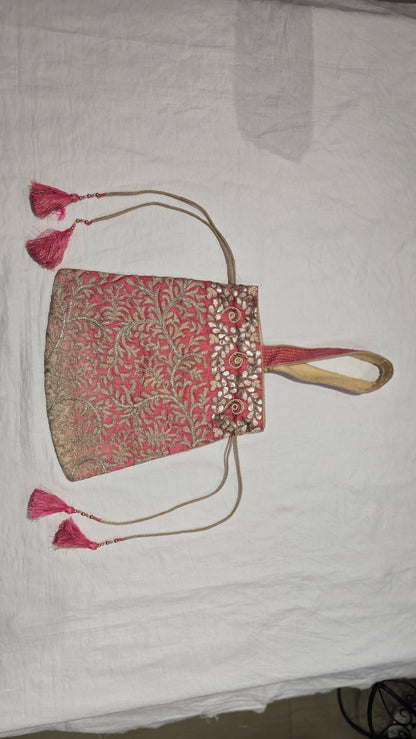 Decorative pink handbag with tassels on a white background