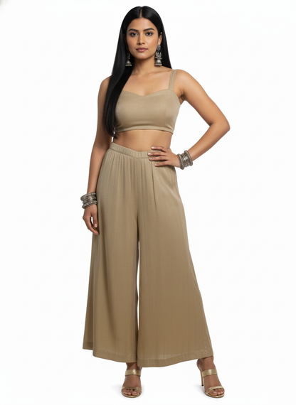 Woman wearing a beige top and plazzo pant on a white background