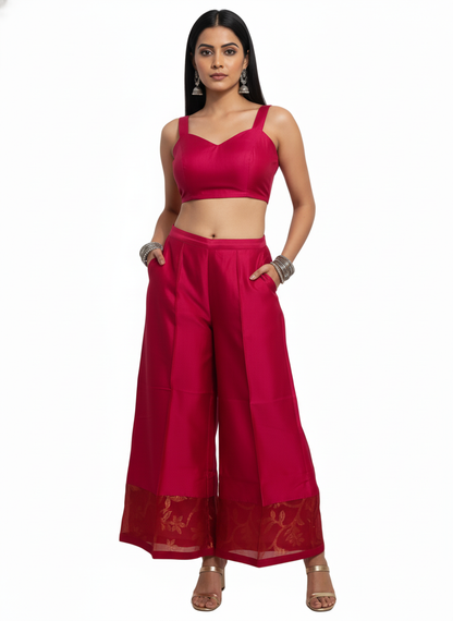Woman wearing a pink plazoo with a matching top on a white background