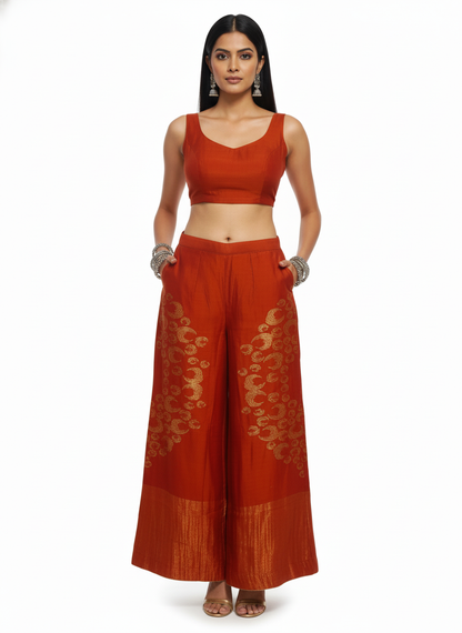 Woman wearing a traditional plazzo pant with a rust top and on a white background