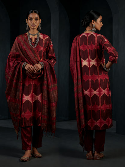 Woman wearing a red patterned kurta with red dupatta on a dark background